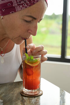 Mature woman enjoying a fresh fs Teh Nusantara tea drink at a window