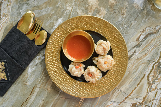 Elegant dumpling serving on a golden plate with sauce