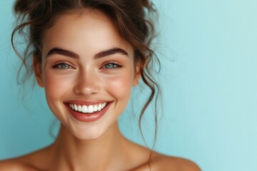 A close-up shot of a woman with flawless white teeth, smiling against a gentle blue backdrop