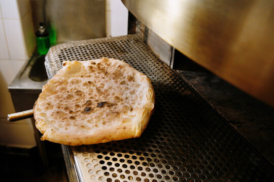 Freshly baked pizza on metal countertop in kitchen