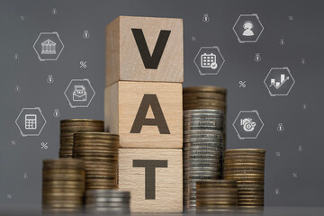 ułożone monety, obok kostki drewniane z napisem vat, w tle ikony dotyczące rozliczeń podatkowych © siwyk