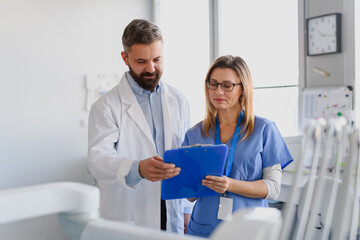 Doctor and female nurse looking at test results in clipboard. Healthcare workers in Doctor's Office.