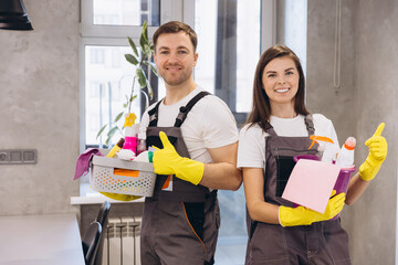 Cleaning company staff holding cleaning products showing thumbs up