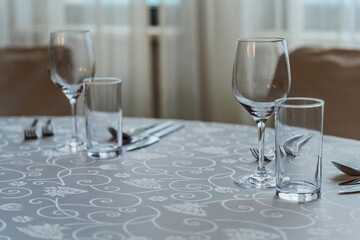 Elegant dining table arrangement featuring empty wine glasses, cutlery. For celebrations or events. Highlights simplicity, elegance, and invites a sense of hospitality.