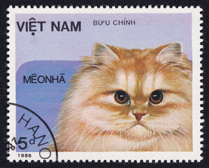 A fat, fluffy white cat is depicted on an old vintage cancelled postage stamp printed in Vietnam...