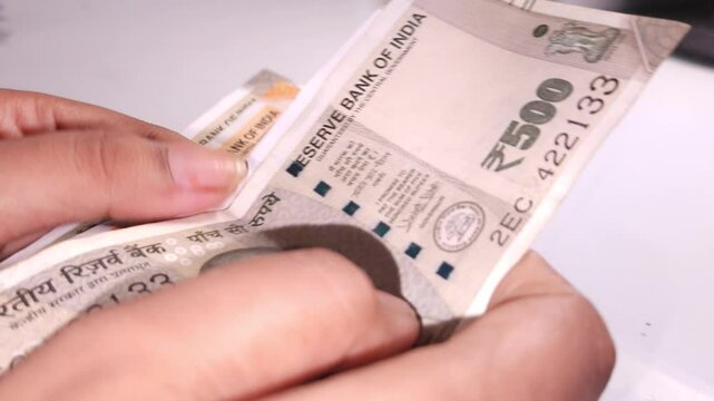 Close up view of woman's hands counting Indian currency notes (INR). Indian cash money of 500, 200 and 100 rupees denominations.