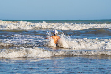 young child boy playing on the waves of the sea in the summer. the concept of active vacation and active life.