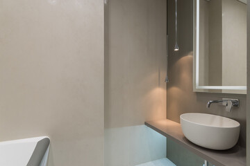 Bathroom in pastel colors. Illuminated mirror over the sink bowl. Stylish lamps.