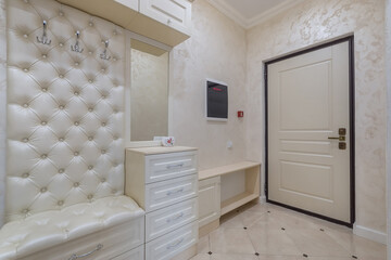 The interior of the hallway, decorated in pastel colors. Light beige entrance door, modern intercom screen on the wall.