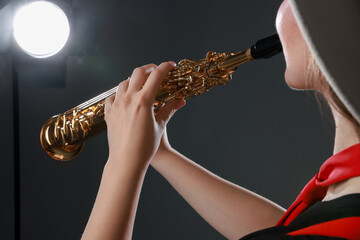 Musician playing soprano saxophone on grey background, closeup
