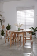 Stylish wooden table with chairs and decor indoors. Interior design