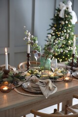 Christmas celebration. Festive table setting with dishware, glasses and decor in room
