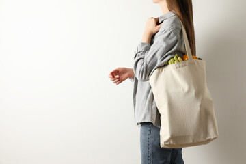 Woman holding shopper bag with groceries on white background, closeup and space for text. Eco...