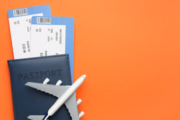 Travel agency. Flight tickets, passport and plane model on orange background, top view. Space for...