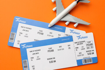 Travel agency. Flight tickets and plane model on orange background, flat lay