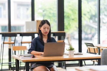Fototapeta premium Young Woman Working on Laptop in Bright Office