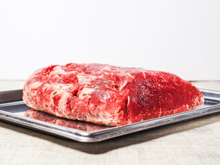 Top quality striploin roast on a metal tray. Premium expensive meat for cooking. Uncooked, raw beef meat in one big piece. Light color background.