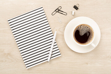 Notebook with cup of coffee on wooden background, top view