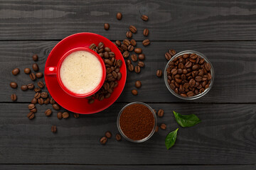 Cup of coffee with coffee beans and leaves on wooden background,top view