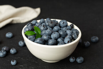 Bowl with fresh bright blueberries on wooden table