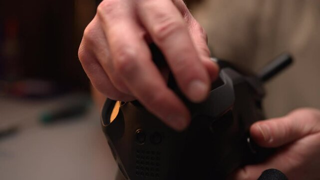 Cropped shot of skilled technician installing or adjusting antenna on drone remote control, ensuring optimal signal transmission and control during flight operations, close-up, slow motion.