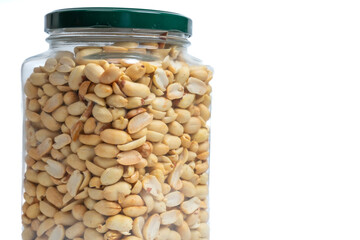 Glass jar with green lid filled with peanuts on isolated white background. Close up of snack peanut filled jar. Nutrition, storage, health and vegetarian concept. Copy space