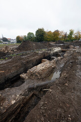Excavation of ancient city walls reveals historical structures in a muddy landscape