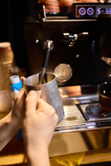 The skilled barista meticulously steaming milk to create beautiful espresso art for customers