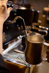 The skilled barista meticulously steaming milk to create beautiful espresso art for customers