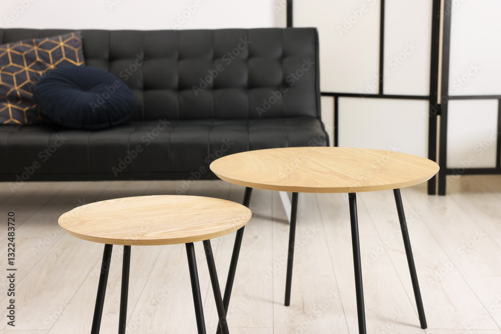 Poster nesting tables and comfortable sofa in room. interior design