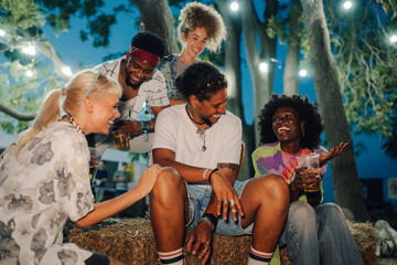 Friends laughing and drinking beer at music festival at night
