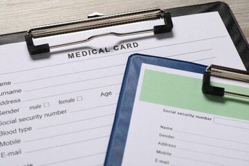 Medical card forms on light wooden background, closeup