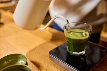 Pouring exquisite Matcha Tea into a stylish Glass while enjoying the serene atmosphere