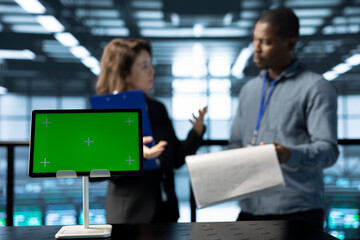 Focus on mockup tablet in front of data center inspector reviewing paperwork files next to manager....