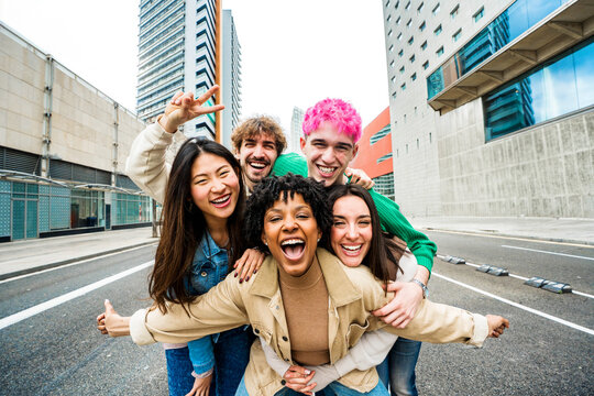 Happy multiracial friends having fun on city street - Group of young people smiling at camera outside - Friendship concept with guys and girls walking in downtown road