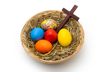 Hand Painted Christian Easter Eggs and Wooden Cross in Wicker Basket with Hay Isolated on White Background
