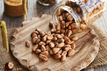 Hazelnuts spilled from a glass jar, with a jar of nut butter in the background