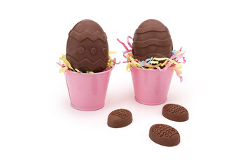 Home Handcrafted Chocolate Easter Eggs with Zig-Zag Pattern in Pink Buckets Next to Chocolate Candies – Festive Holiday Child Treat Activity