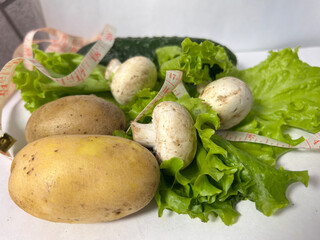Fresh vegetables salad cucumber potatoes mushrooms, with measuring tape, quality
