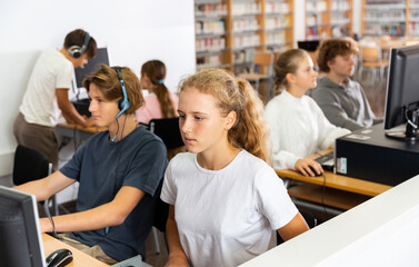 Fifteen-year-old schoolgirl, studying at school in an informatics lesson in the classroom, sitting at the computer
