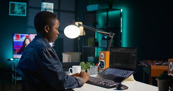 Software developer writes code on laptop screen while in apartment office using Java programming languages. Programmer remotely working on fixing database errors while working from home, camera B