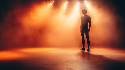 Fototapeta premium Silhouetted person standing on stage in orange spotlight.