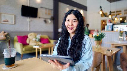 Businesswoman consultant motivation concept. A young woman smiles while using a tablet in a cozy cafe setting.