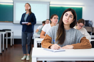 Young female student attentively listening to a lecture in a classroom