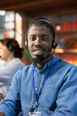 Fototapeta premium Portrait of smiling call center operator talking in audio headset mic, providing step by step guide to customer. Upbeat customer center employee speaking in headphones microphone, providing technical