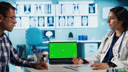 Indian physician consulting a patient in medical facility next to chroma key, using modern tech for scan interpretation and results. Medic giving professional advice based on records. Camera B.