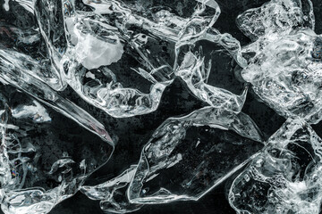 Pieces of crushed ice on black background. Abstract ice structure background, top view