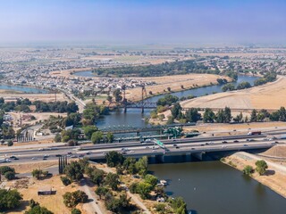Aerial view of San Joaquin River, Lathrop, California,  USA, with I-5 highway bridge. Cars and trucks are traveling across the bridge, connecting communities and facilitating commerce.