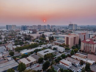San Jose, USA, skyline at sunset. The sun is a red orb due to smoke from wildfires. The city is a...