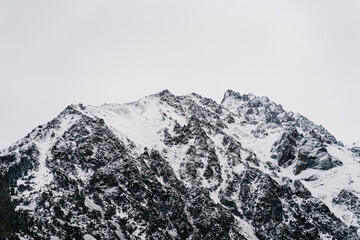 Majestic snow-capped peaks of Kyrgyzstan rise against a cloudy sky in a tranquil winter landscape